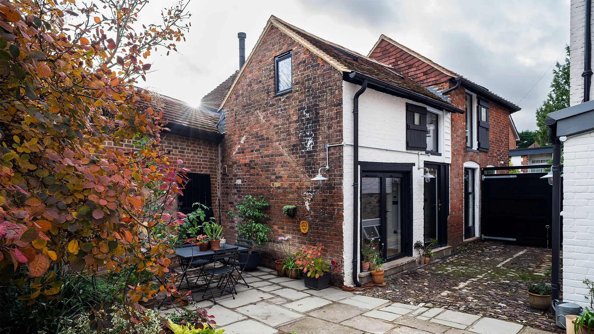 Charming brick courtyard with plants and patio furniture. Grade II listed building and outbuilding in heritage setting